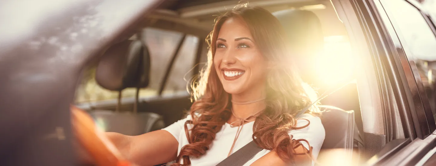 Smiling driver in car on a sunny day.