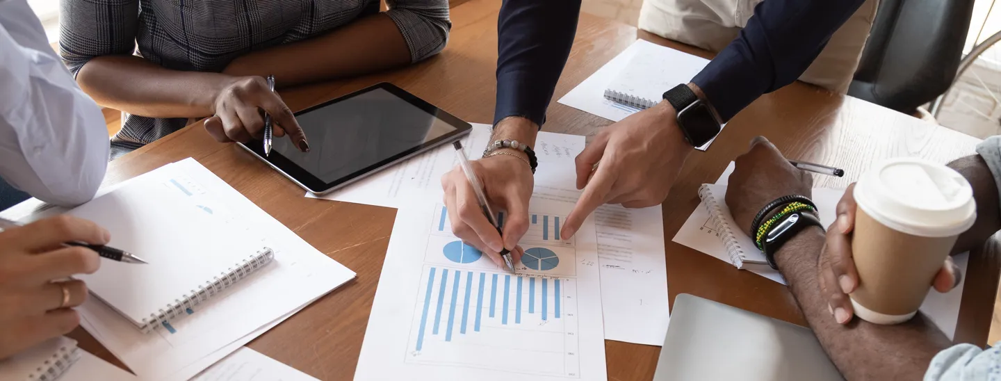 Business owners reviewing financial charts and valuation reports during a meeting, discussing business value and succession planning.