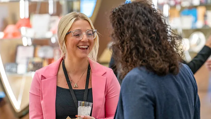 Employees engaged in a professional conversation during a workplace event, representing competitive pay, benefits, and collaborative company culture.